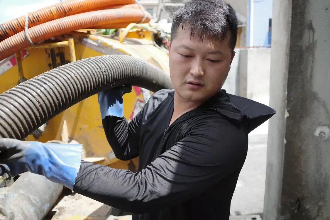 ▲工作时,潘浩男需要拖着几十公斤重的抽粪管 红星新闻记者 付垚 摄
