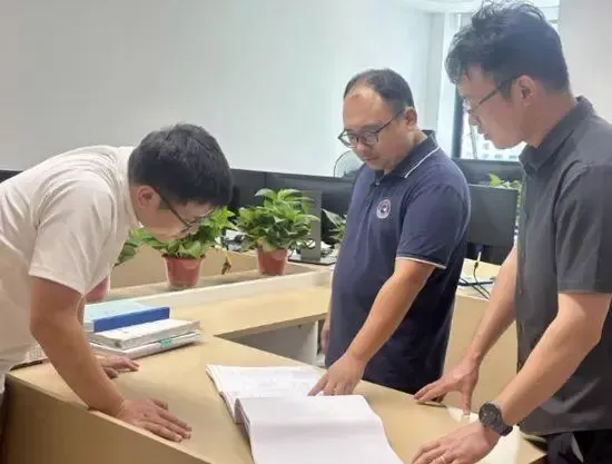 2025年7月25日，彭湃（中）与同事交流施工图纸。