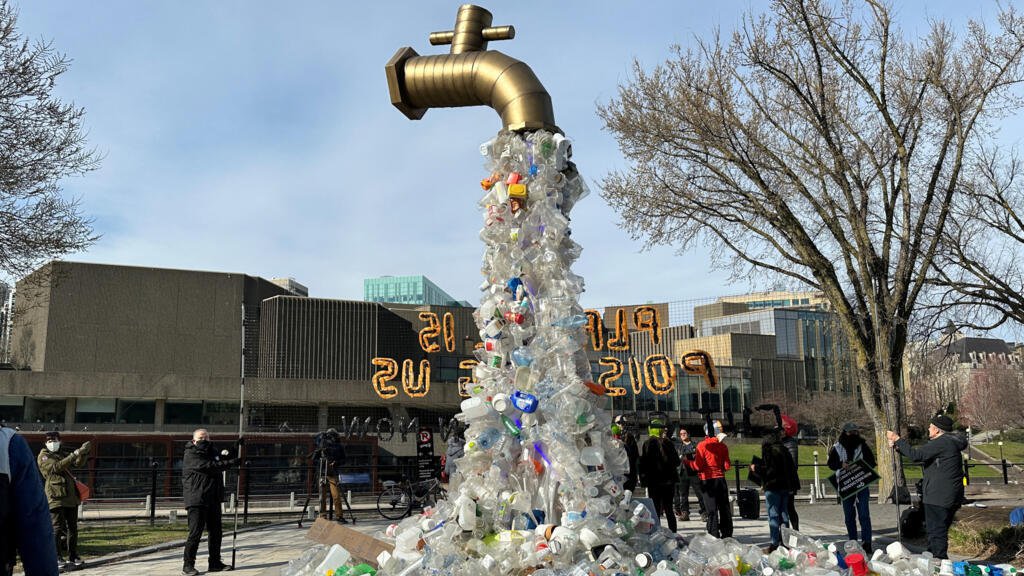 Une installation représentant un robinet d'eau avec des bouteilles en plastique en cascade est exposée par des activistes près du Centre Shaw, lieu de l'avant-dernière négociation du tout premier traité mondial sur les plastiques, à Ottawa, Ontario, Canada, le 23 avril 2024.