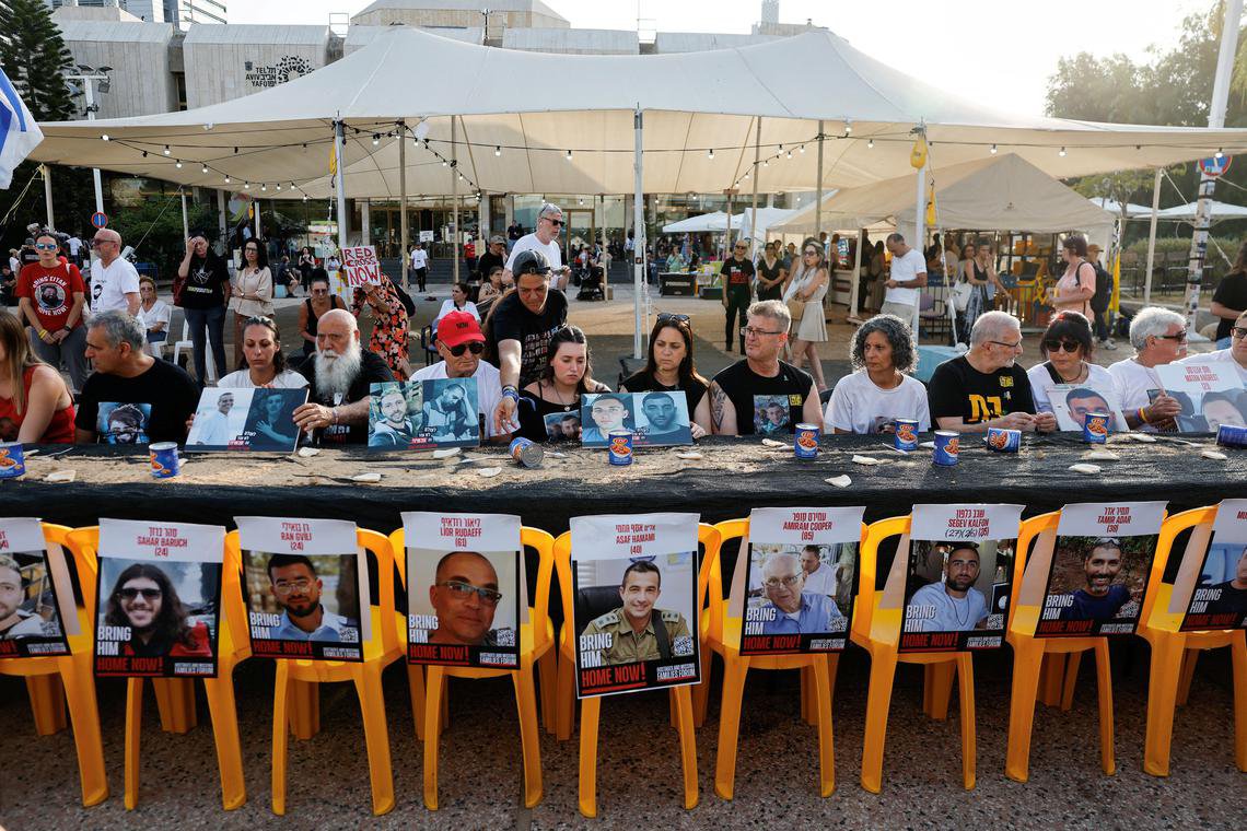 以色列人质家属周六在特拉维夫参与反对扩大加沙军事行动的示威活动,他们坐在摆放着罐头食品和掰成四等份的皮塔饼的桌前,以此凸显人质的严峻处境。 (路透社) 以色列人质家属周六在特拉维夫参与反对扩大加沙军事行动的示威活动,他们坐在摆放着罐头食品和掰成四等份的皮塔饼的桌前,以此凸显人质的严峻处境。 (路透社)