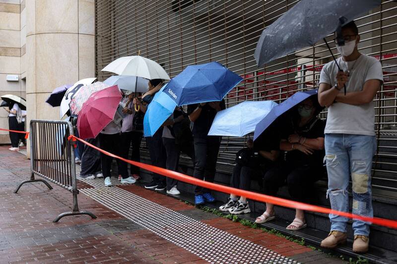 大批香港市民18日冒雨在法院外排队，希望能进入法庭旁听黎智英案的结案陈词，以示支持。（路透）