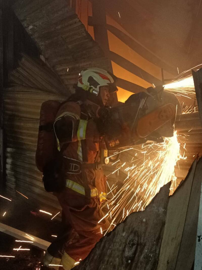 由于铁皮屋有坍塌危险，消防破门寻找火点。（警方提供）