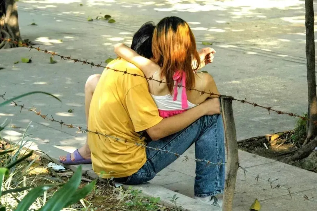 2006年8月13日，广东东莞，打工人在工厂外的绿化带旁拍拖