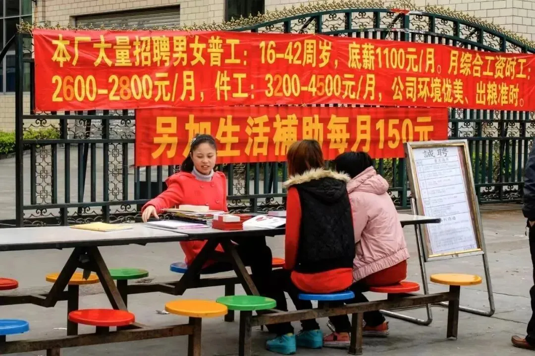 工厂的大门外摆着招聘摊儿，招聘就在厂门口直接进行。