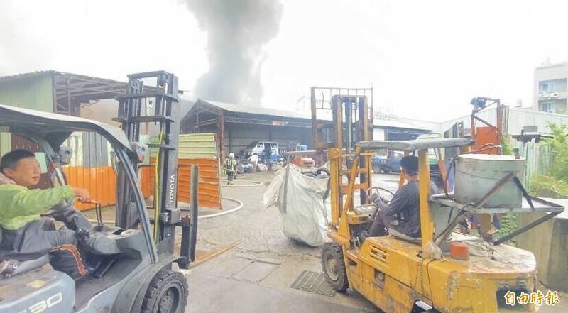 桃园区树仁三街网拍仓库火灾有扩散到后方废车辆与废轮胎回收场之虞，回收场奈及利亚裔张姓男负责人与员工、邻近业者协助，出动多部推高机吊挂废轮胎到场外的道路暂放。（记者陈璟民摄）