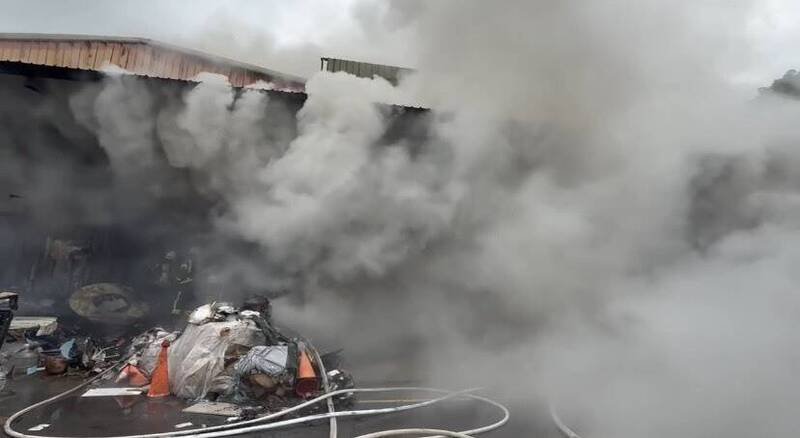 桃园市桃园区树仁三街今早惊传仓库火灾，浓烟密布，场内疑有1男1女员工受困，消防单位射水灭火并搜救人员。（图由桃园市消防局提供）