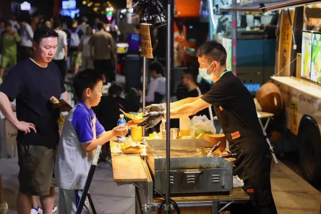 地摊市集上购买小吃的消费者 / 新华社记者王翔 摄