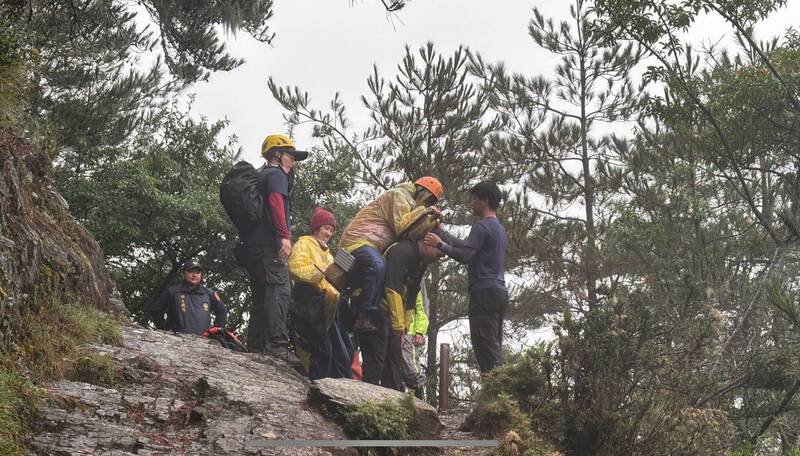 彭女因高山症发作，由警消人员背负下山。（图由警方提供）