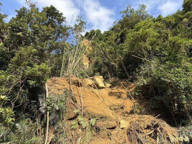 基隆暖暖兴隆街边坡坍塌，上方还有多颗浮石，最上方的大石节理有裂缝，有掉落风险。（记者卢贤秀摄）