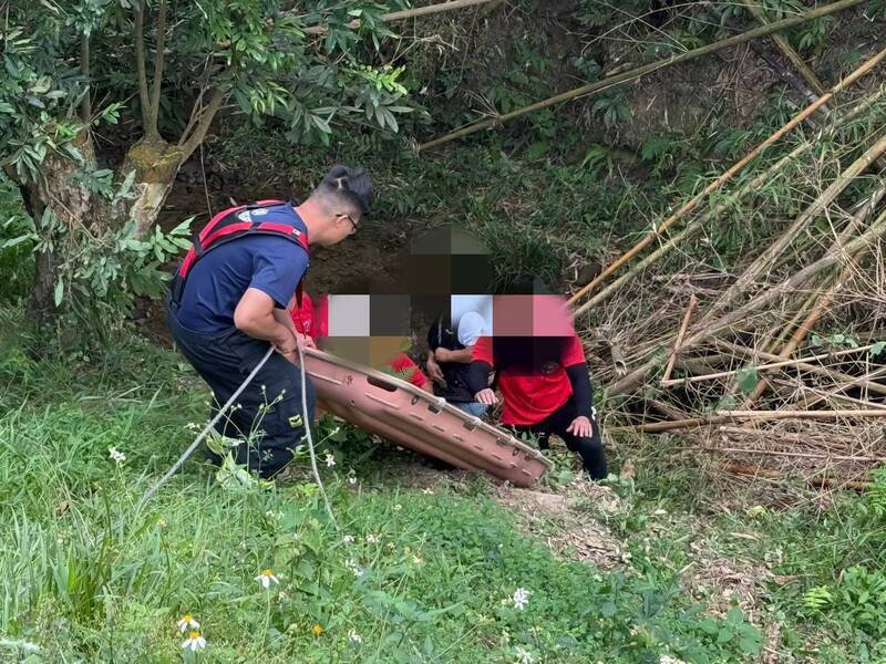 救援人员将坠落斜坡溪边的罗翁救起。（嘉义市消防局提供）