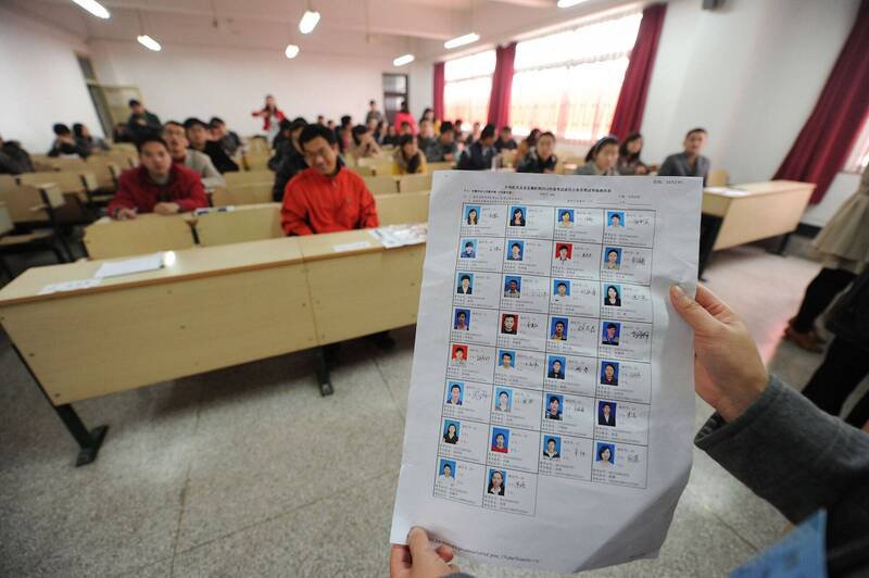 中国安徽合肥市公务员国考试场，监考人员核对附有照片的考生名单。（法新社）