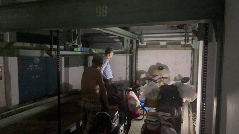 郭男寄生在大楼地下室故障的机械停车位2年多，上头堆满床舖、家当等物品，连机车都能停入。（民众提供）