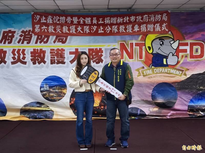 鑫悦排骨餐饮公司负责人王亭媁（左）代表公司与全体员工，捐赠 1辆高顶救护车给汐止分队，由消防局专门委员陈志玮（右）代表受赠。（记者林嘉东摄）